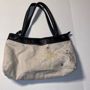 Thirty-One cream flower purse with black leather straps.